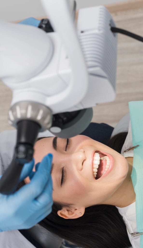 Image of a dental checkup: A patient, seated in a dental chair, undergoing a dental examination. The patient's mouth is open as a dentist, probe to inspect the teeth. The setting is a well-lit dental office with modern equipment visible in the background, emphasizing dental care and professionalism.